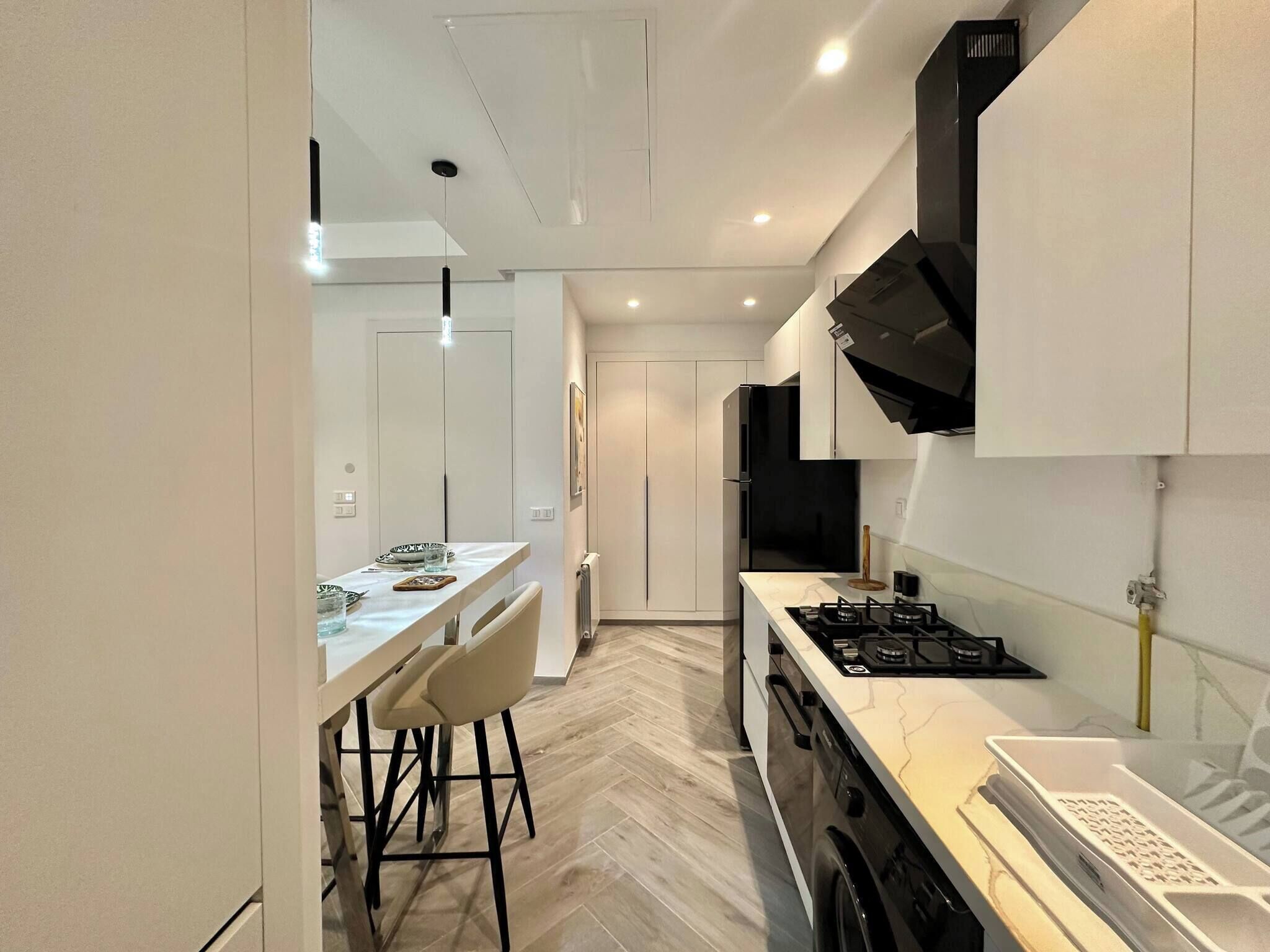 A modern kitchen with a central island, a stove, and a dining area with chairs.