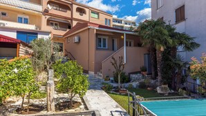 A multi-story residential building with balconies, a swimming pool, and a garden with various plants. - Attic apartment with WiFi, air conditioning and private parking space (Crikvenica)