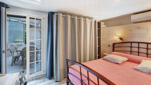 Ein Schlafzimmer mit Bett, einer Glasschiebetür zu einem Außenbereich und einem hölzernen Kopfstück.