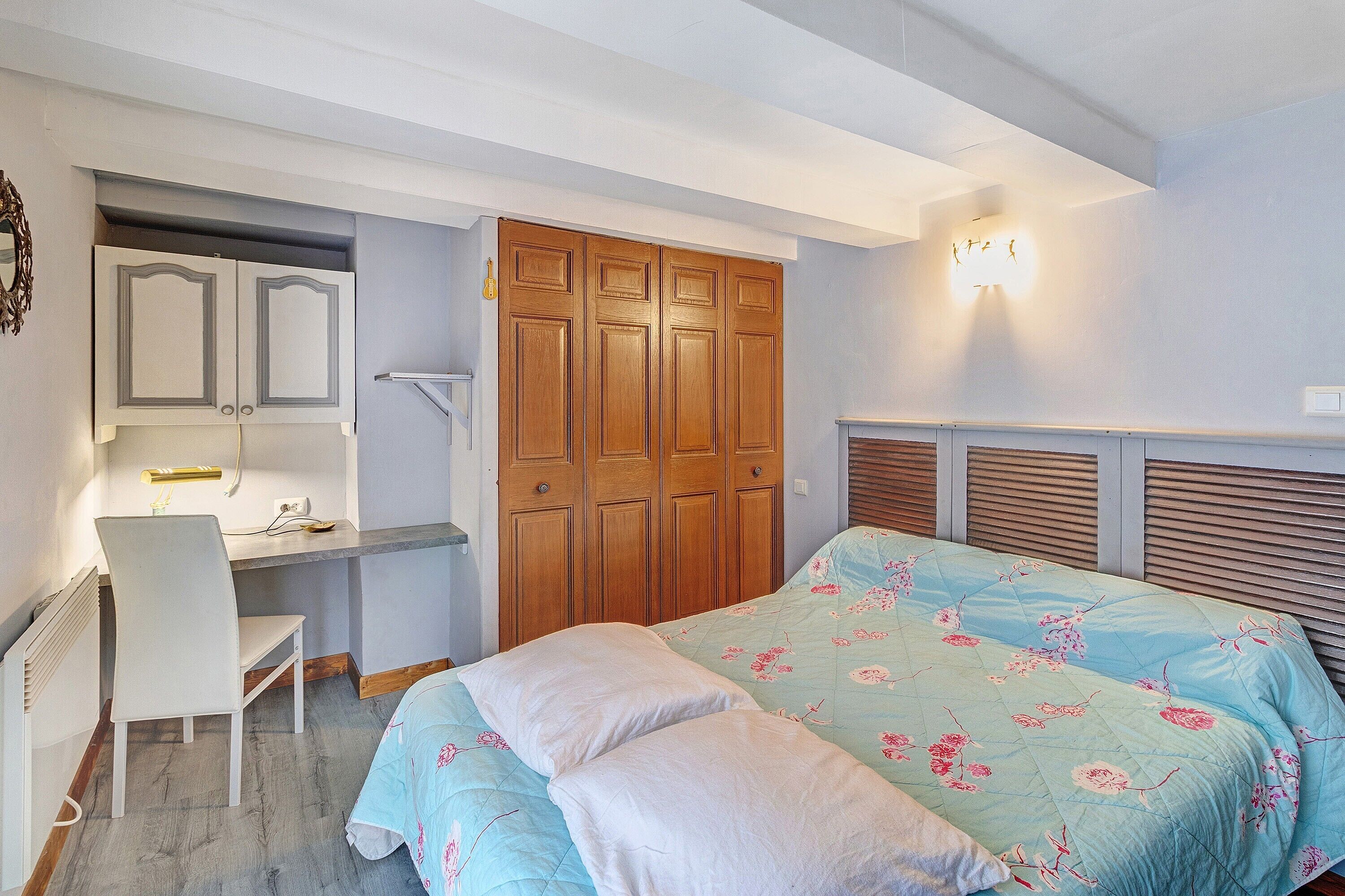 Une chambre à coucher avec un lit, deux oreillers, un bureau avec une chaise et une armoire.