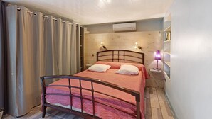 Ein Schlafzimmer mit Bett, Vorhängen, einer Nachttischlampe und einer Wand-Klimaanlage.