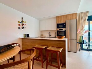Eine moderne Küche mit weißen Schränken, einem schwarzen Wasserhahn, einer Holztheke und einem Edelstahlkühlschrank.