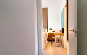 Een hotelkamer met een bed, een bureau, een stoel, een lamp en een wandplank.