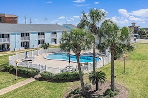 A hotel with a pool, palm trees, and a white fence. - ~ 1Br/1Ba ~ Gulf View ~ Pool ~ Tradewinds 33 ~ (Miramar Beach)