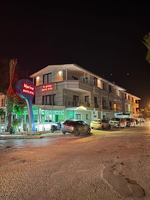 Un hotel de varios pisos con un cartel que dice 'Marina Suite Hotel' y una decoración de palmera.