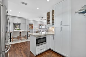 A modern kitchen with white cabinetry, a central island, and a built-in oven. - Warm Florida Sun with Spectacular River Views in Peaceful Active Community (Stuart)