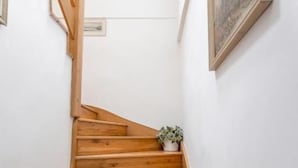 Een houten trap met witte muren en een ingelijst kunstwerk aan de wand.