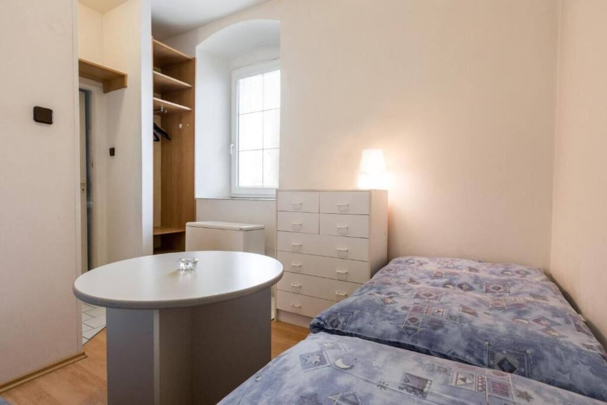 A bedroom with a bed, a bedside table, a dresser, and a window.