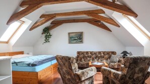 Een loftachtige kamer met een houten plafond, een bed, een bank en een kleine tafel.