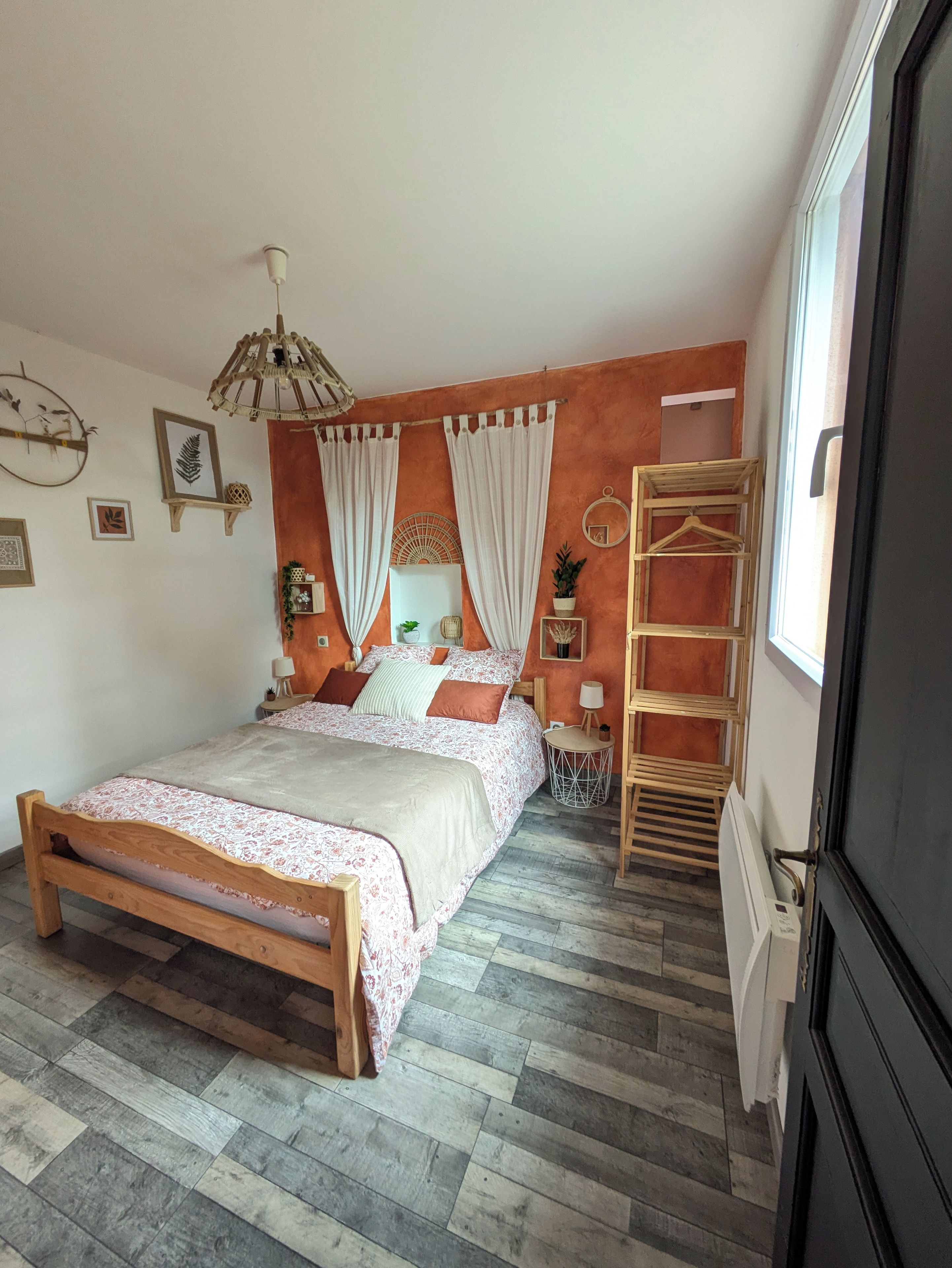A bedroom with a wooden bed, a hanging chair, a ladder, and a window with curtains.