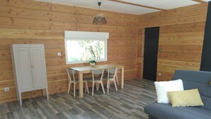 Um quarto com painéis de madeira, um sofá, uma mesa de jantar com cadeiras e um armário.