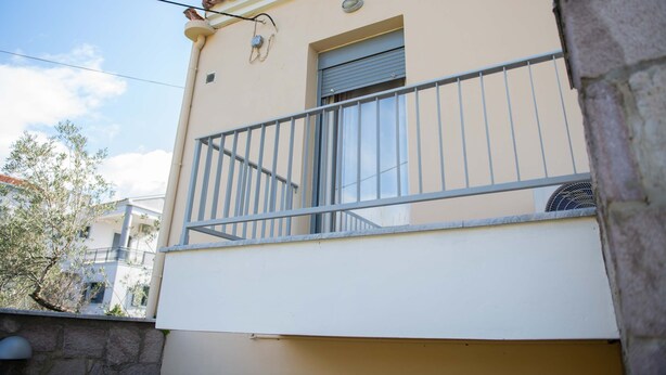 A building with a balcony, a window, and a wall-mounted air conditioning unit. - Loucas Home Kalloni Lesvos Central Stay w Balcony (Lesvos)