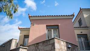 A building with a stone facade, a pink upper wall, and a tiled roof. - Loucas Home Kalloni Lesvos Central Stay w Balcony (Lesvos)