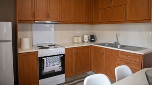 A kitchen with wooden cabinets, a white stove, a sink, and a toaster. - Loucas Home Kalloni Lesvos Central Stay w Balcony (Lesvos)