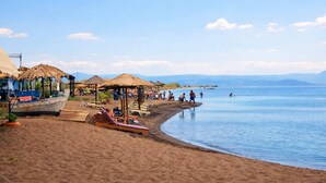 A beach with a boat, sun loungers, and thatched-roof structures. - Loucas Home Kalloni Lesvos Central Stay w Balcony (Lesvos)
