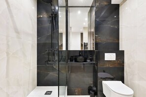 A modern bathroom with a glass-enclosed shower, a toilet, and a sink with a black basin. - Loft de luxe en plein centre-ville (Asnières-sur-Seine)