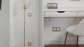 Et lyst rum med en rund gulvlampe, et hvidt skrivebord med et spejl og en blød stol.