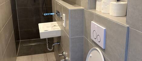 A modern bathroom with a toilet, sink, and shower area.