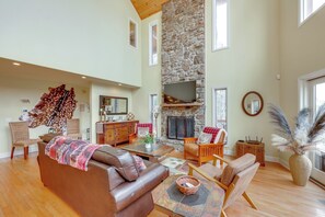 A spacious living room with a stone fireplace, leather sofa, wooden coffee table, and a large window. - On 80 Acres! Rural 'sunset Lodge' in Hot Springs (Hot Springs)