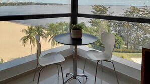 Una habitación con un ventanal grande, una mesa redonda con dos sillas y una planta en maceta.