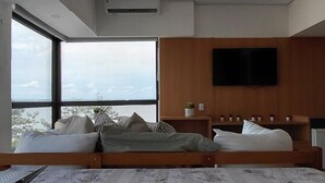 Un dormitorio moderno con una cama grande, un televisor montado en la pared y una ventana con vista al cielo.