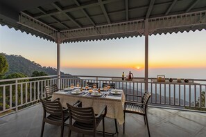 A terrace with a table set for dining, overlooking a mountainous landscape. - ELIVAAS Alpenglow 3 BHK Villa (Kasauli)