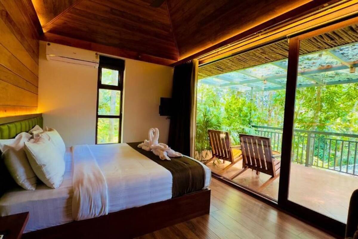 Een slaapkamer met een bed, een groen hoofdeinde, een raam en een balkon met een stoel.
