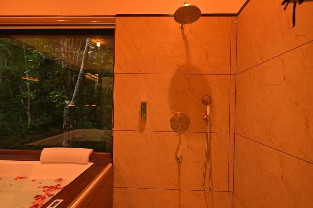 Ein Badezimmer mit Dusche, Badewanne und einem Fenster mit Blick auf Bäume.