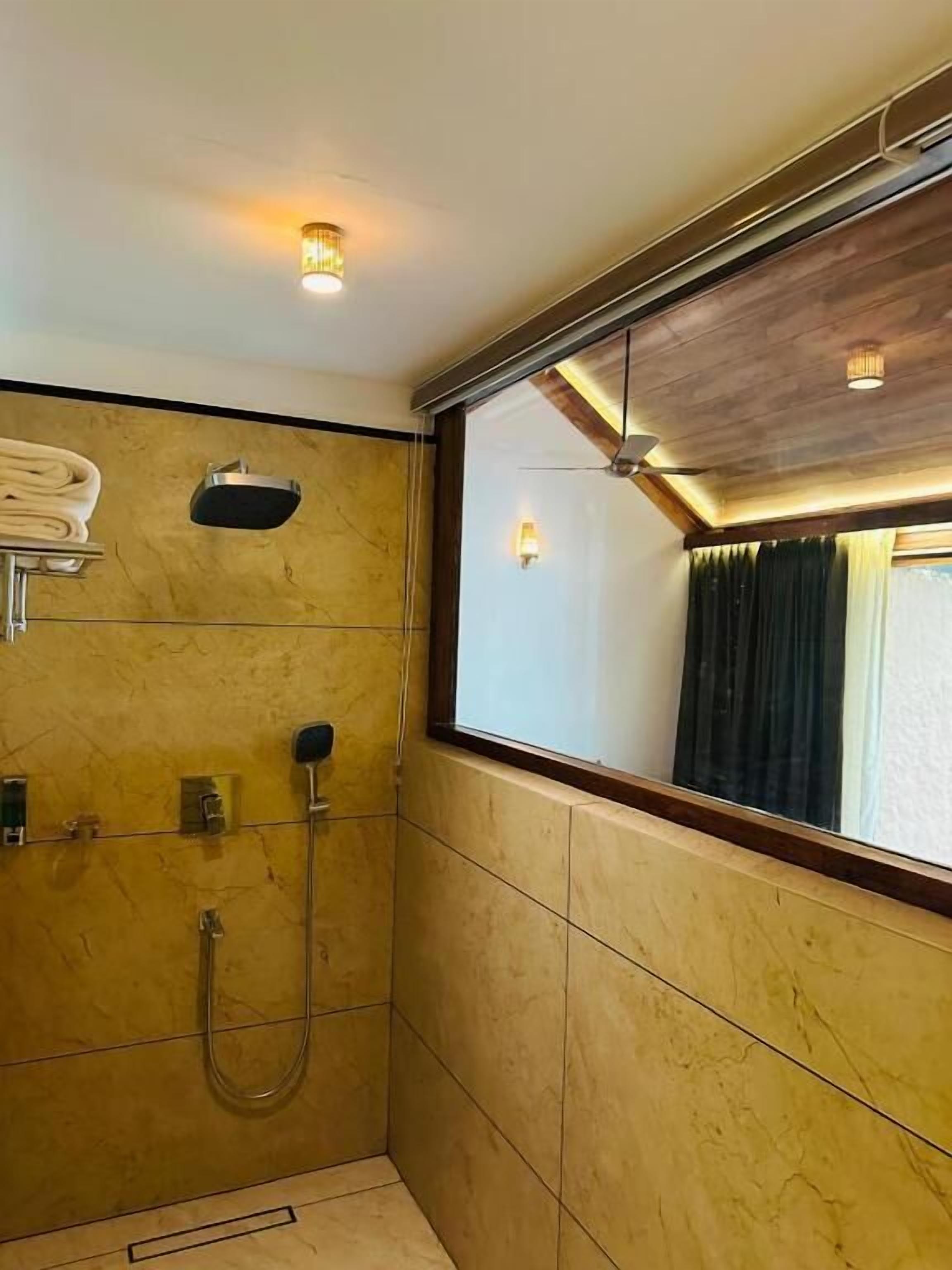 Une salle de bain avec une douche, un porte-serviettes et une fenêtre avec des rideaux.