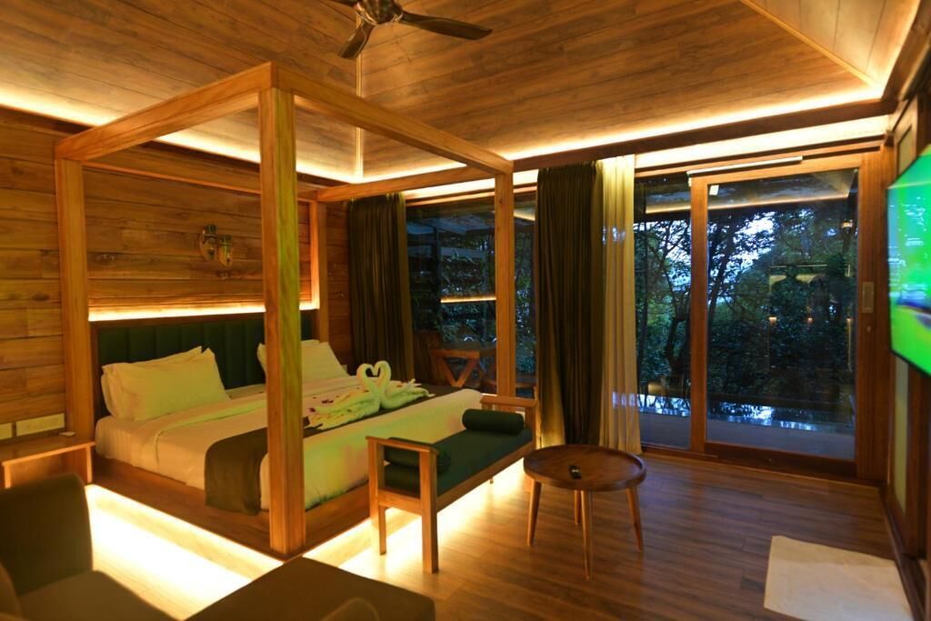 Un dormitorio estilo cabaña de madera con una cama con dosel, una mesita y vistas al exterior.