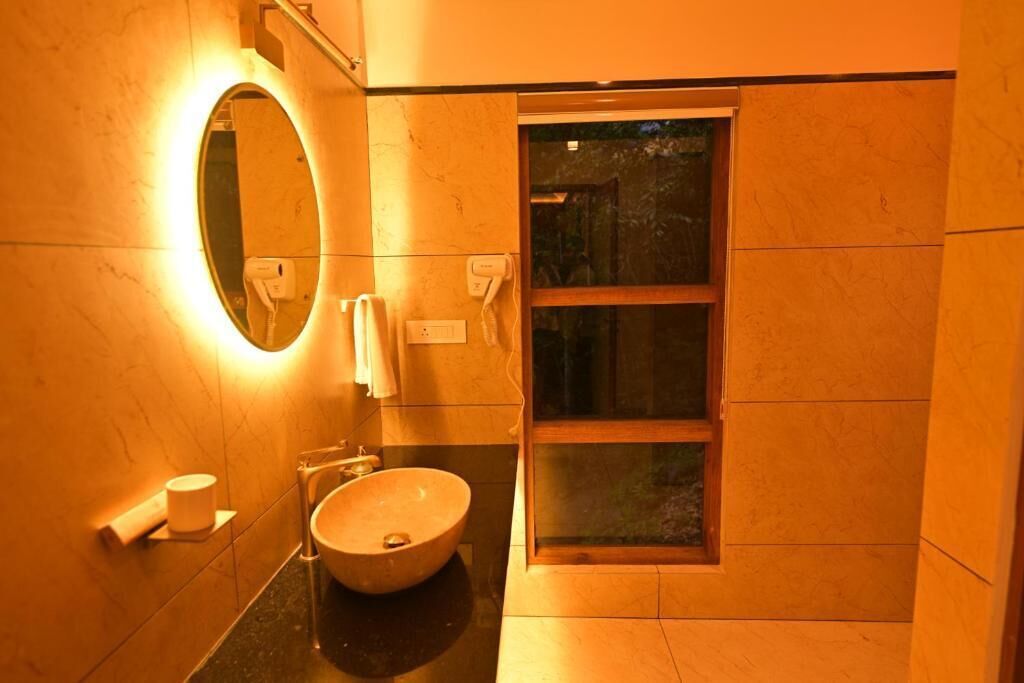 A bathroom with a round mirror, a sink, a towel rack, and a window.