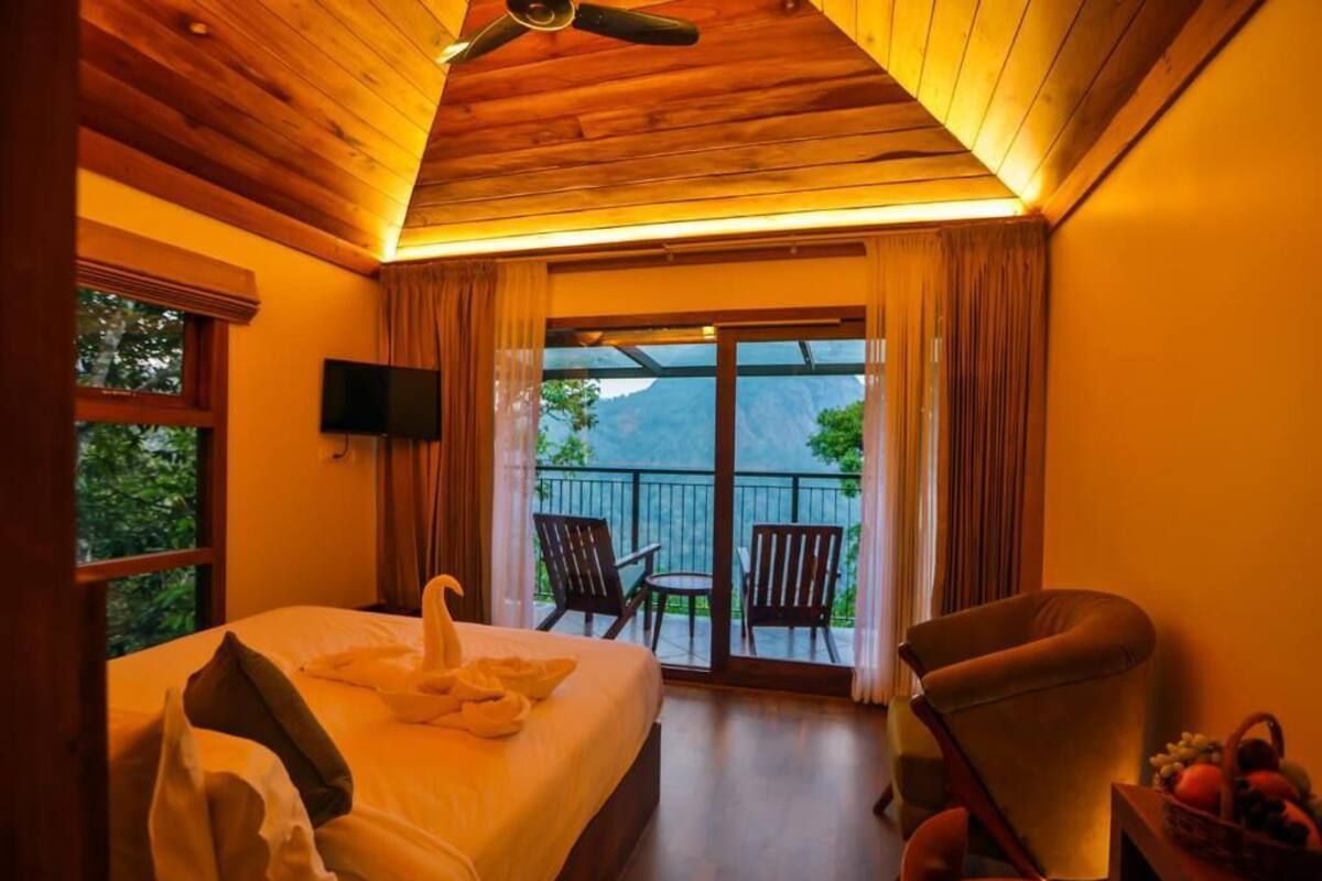 Een hotelkamer met een bed, een televisie, een balkon met stoelen en uitzicht op de omgeving.