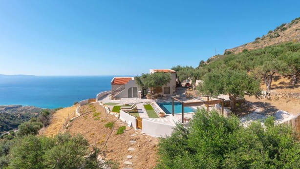 Una villa costera con piscina, jardín escalonado y vistas al mar.
