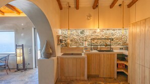 Una cocina compacta con salpicadero de piedra, armarios de madera y una lámpara colgante.