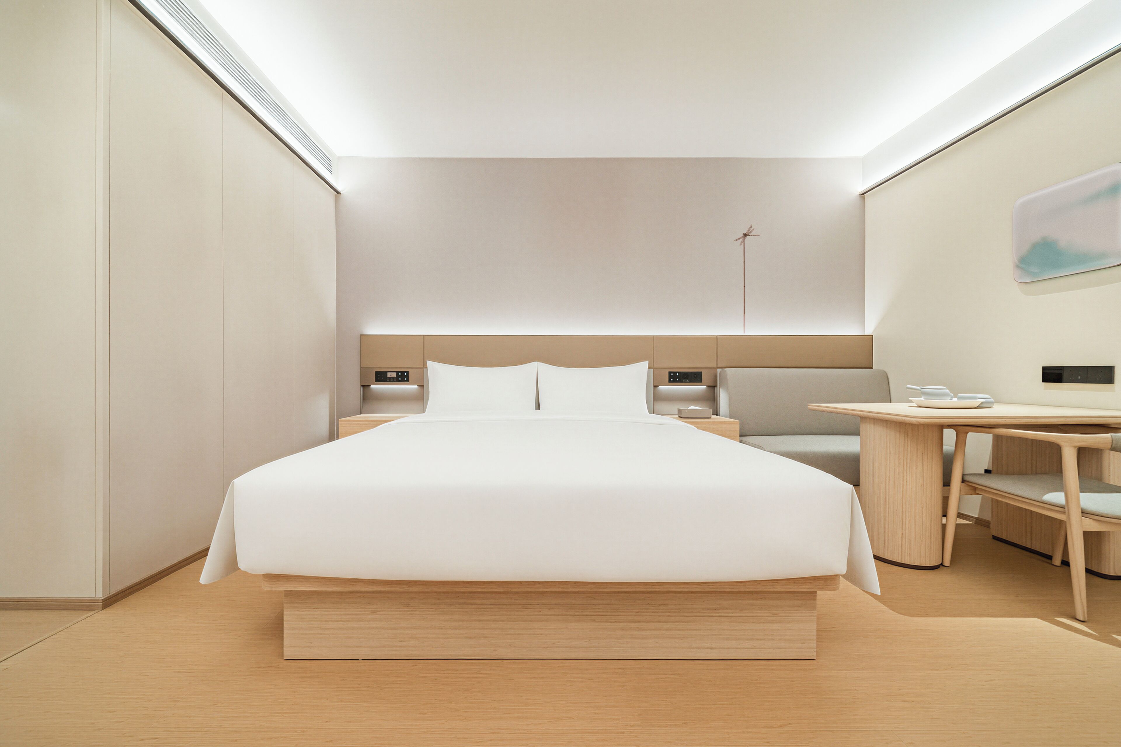 A modern hotel room with a large bed, bedside tables, a desk, and a chair.