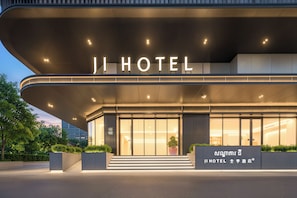 A modern hotel entrance with a large illuminated sign, a glass facade, and a staircase leading to the entrance. - Ji Hotel Phnom Penh Downtown (Phnom Penh)