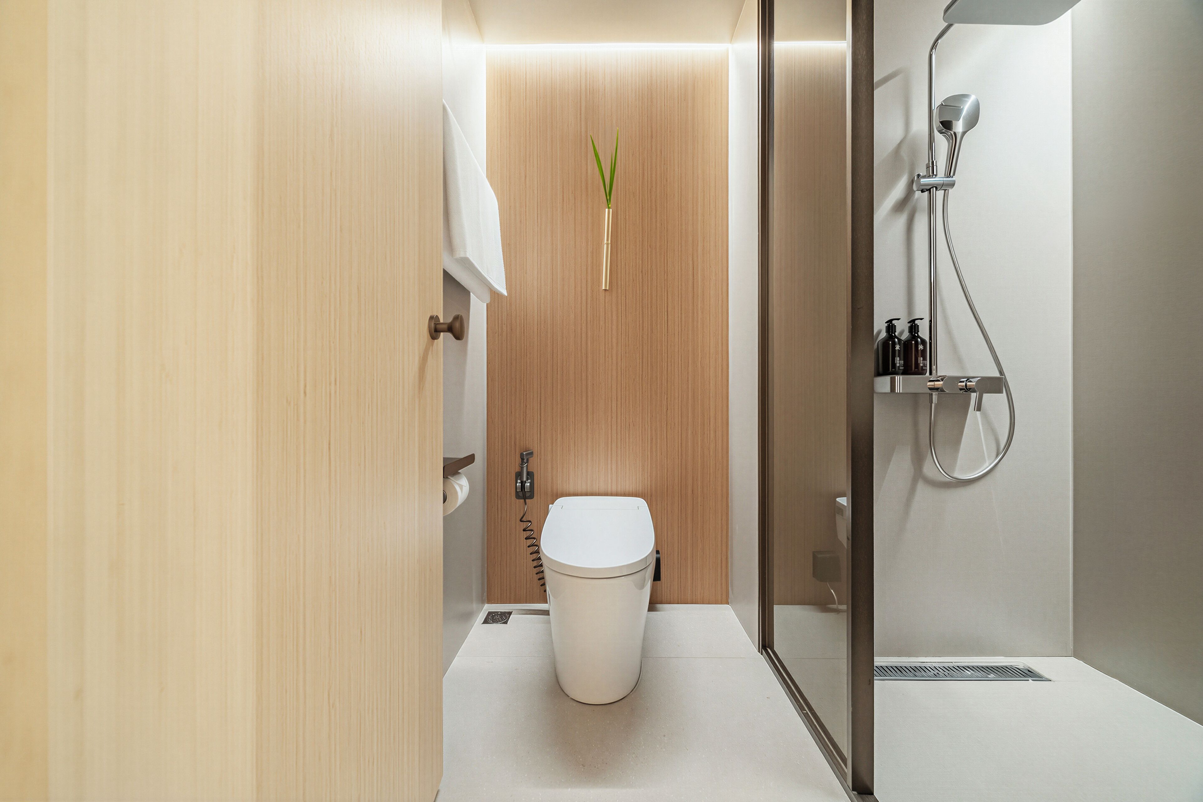 A modern bathroom with a toilet, a shower, and a wooden panel wall.