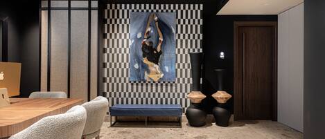 A modern interior with a dining area, a checkered wall, and a painting.