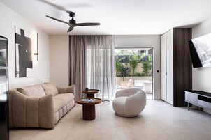 A modern living room with a sofa, armchair, coffee table, ceiling fan, and a TV on a stand.