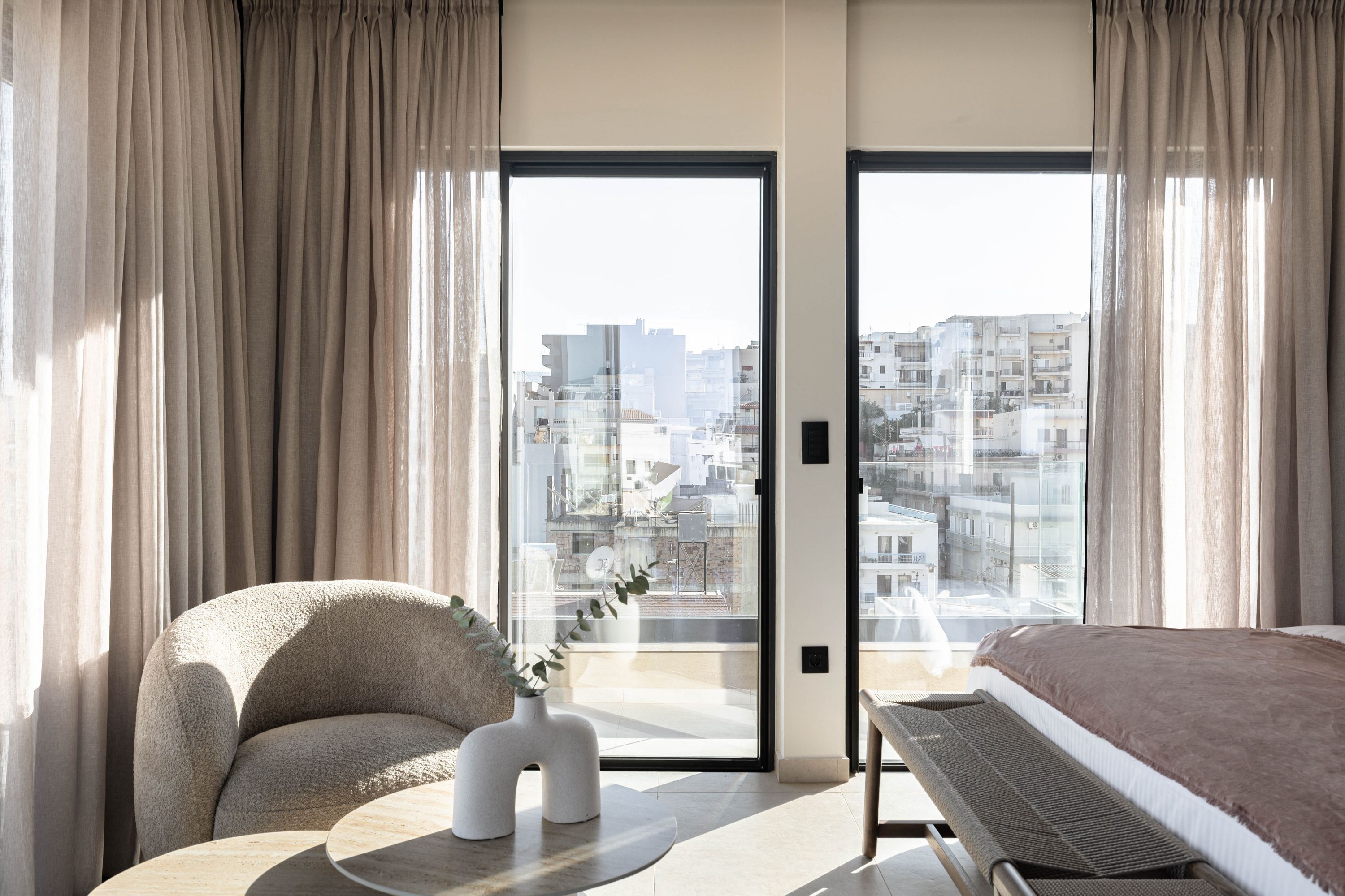 Een moderne hotelkamer met een groot raam, een bank, een tafeltje en een bed.