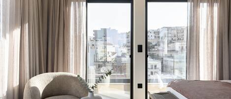 Een moderne hotelkamer met een groot raam, een bank, een tafeltje en een bed.