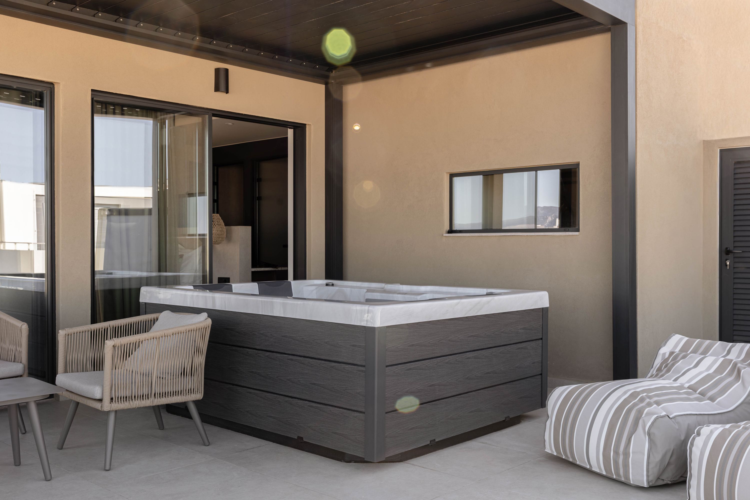 A modern bathroom with a large bathtub, a glass shower enclosure, and a small window.