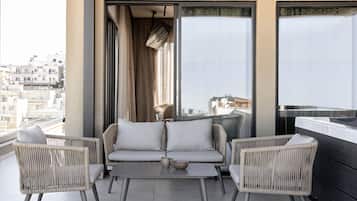 Ein Balkon mit Korbmöbeln, einem Tisch und Blick auf die Stadtlandschaft.