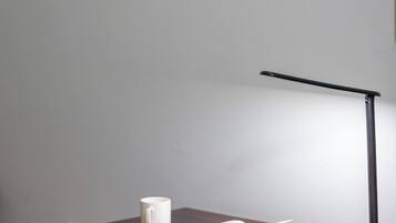 A wooden desk with an open book, a white mug, and a desk lamp.