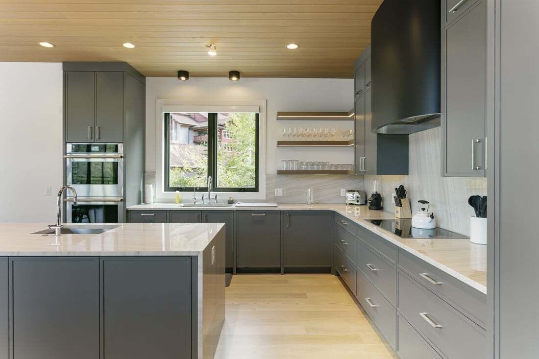 A modern kitchen with grey cabinets, a central island, and a window providing a view.