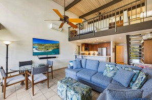 Un vaste espace de vie comprenant un canapé, des fauteuils, un téléviseur et un balcon.