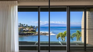 Una habitación con amplias ventanas, techo de madera y vistas al océano y a las montañas.