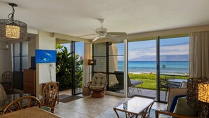 A spacious room with a large sliding glass door leading to a balcony with a view of the ocean. - Oceanfront Maui Point Condo Sleeps 4 - Unit A3 1 Bedroom Condo (Lahaina)
