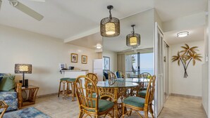 A dining area with wicker chairs, a glass table, and pendant lights. - Oceanfront Maui Point Condo Sleeps 4 - Unit A3 1 Bedroom Condo (Lahaina)