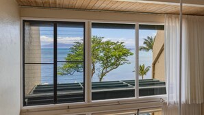 A room with a large window overlooking a body of water and a tree. - Prime Oceanfront 2br Loft - Unit C10 1 Bedroom Condo (Lahaina)